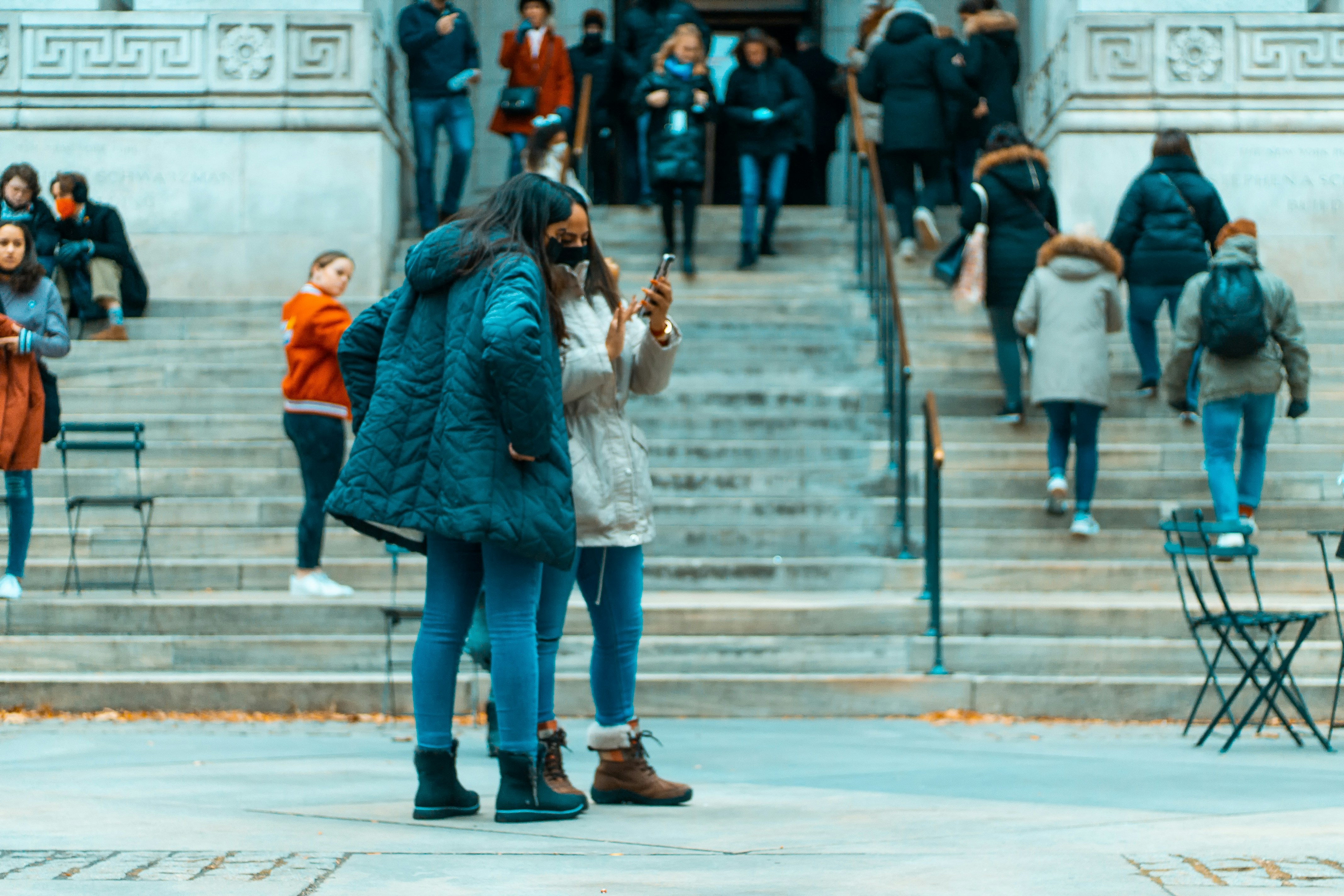 a woman standing in front of a building while looking at her cell phone