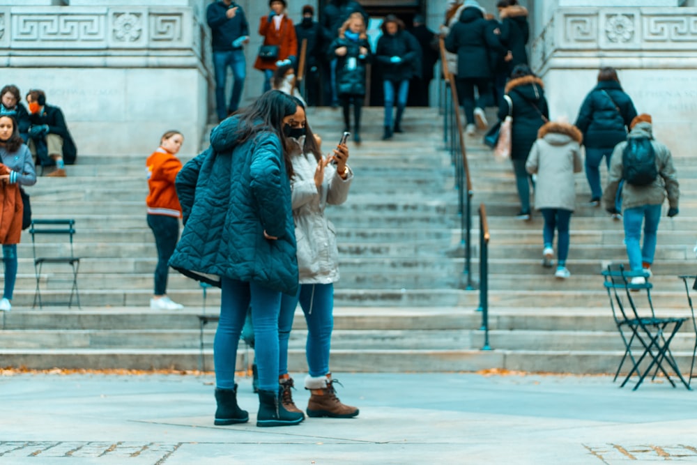 a woman standing in front of a building while looking at her cell phone