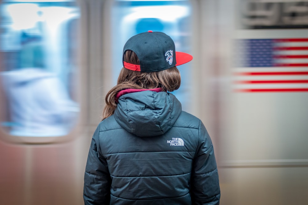 a person wearing a hat and jacket standing in front of a train