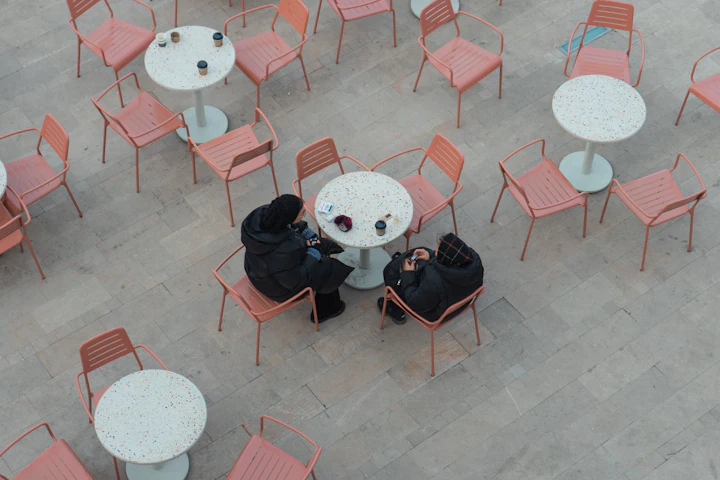 Two people sitting at a table in a courtyard