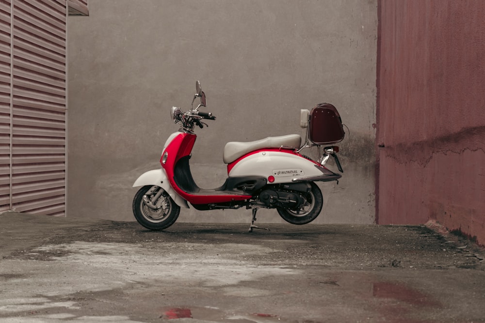 a red and white scooter parked next to a building