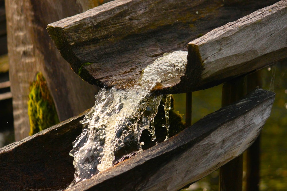 a close up of a wooden bench with water coming out of it