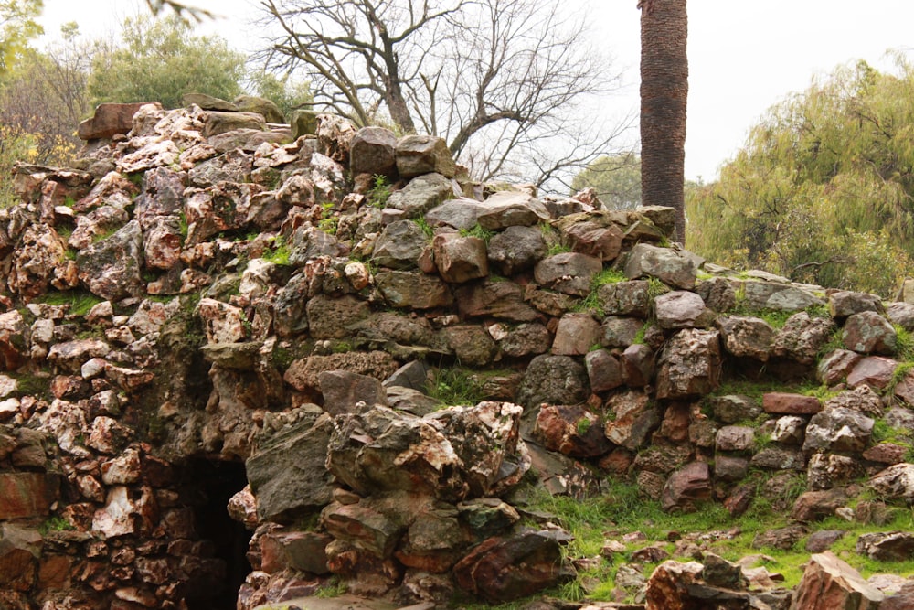 a pile of rocks sitting on top of a lush green hillside