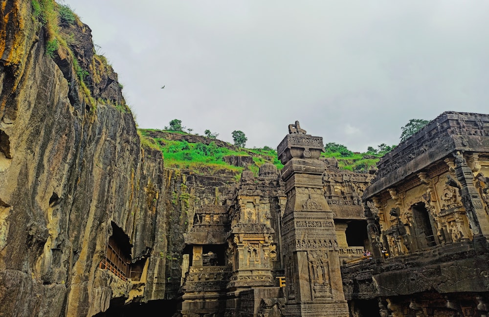 a group of stone structures with a green hill in the background