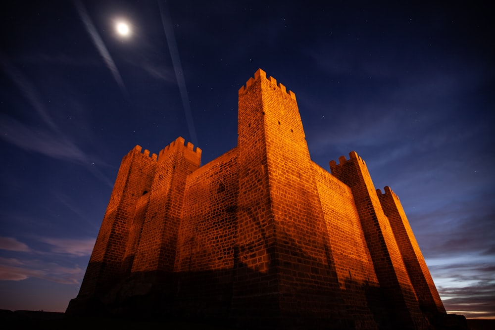 um edifício de tijolos alto com uma lua cheia no fundo