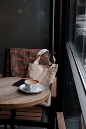 A sleek shoulder bag resting on a cozy café table beside a cup of coffee.