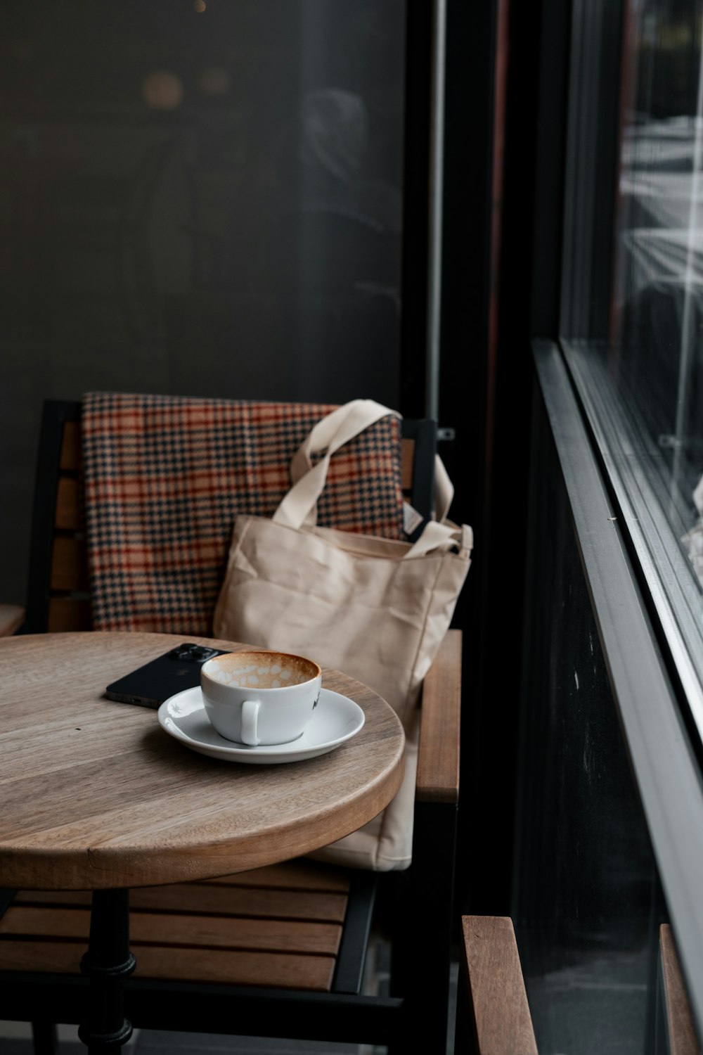 a cup of coffee sitting on a table next to a window