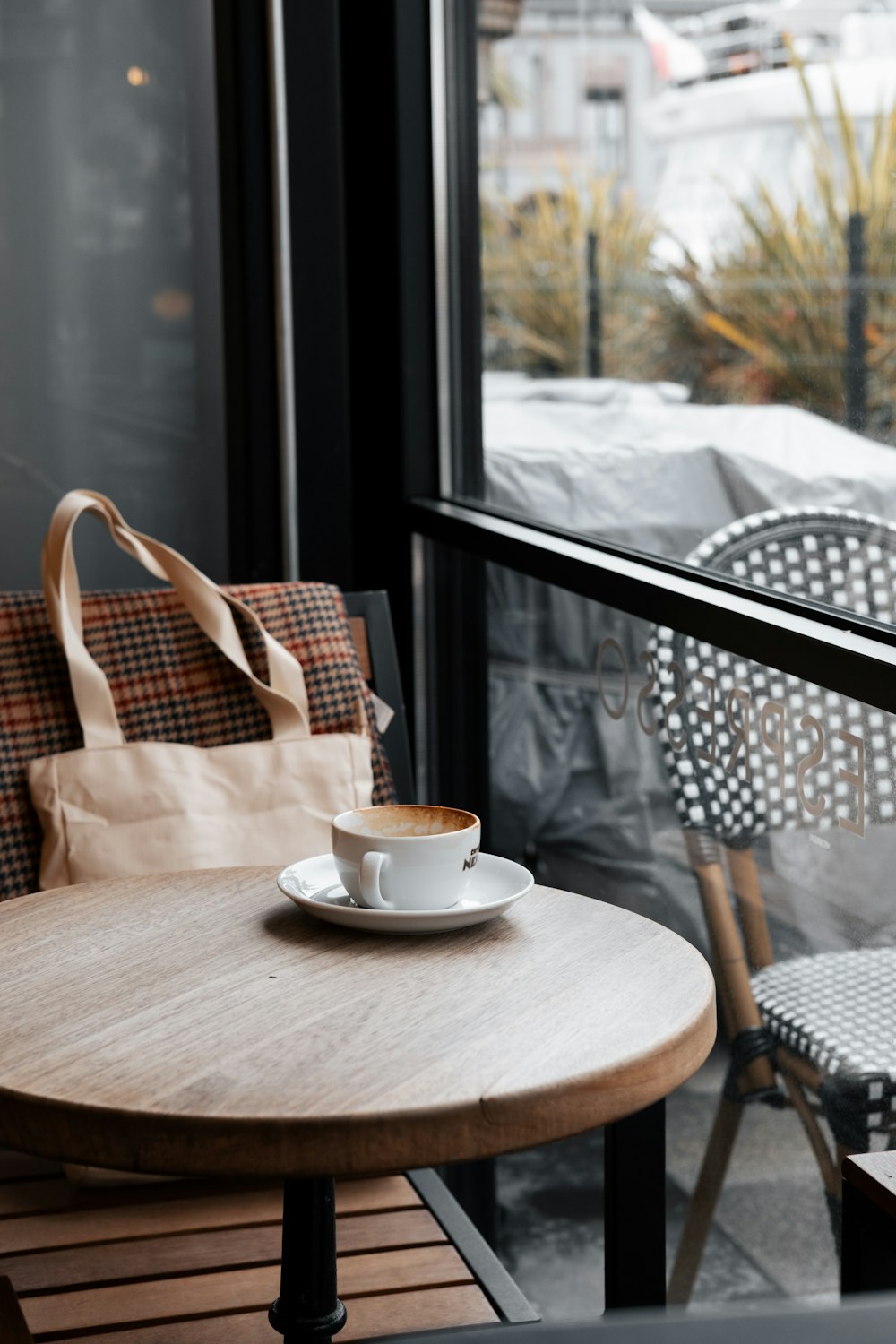 a cup of coffee sits on a table in front of a window