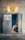 A vintage photo booth with the word 'FOTOAUTOMAT' displayed prominently at the top. The booth is metallic and looks slightly worn. Inside, a person is seated, partially visible with a blue interior background. The floor is stone or concrete, and there are some faint graffiti marks on the booth's exterior.