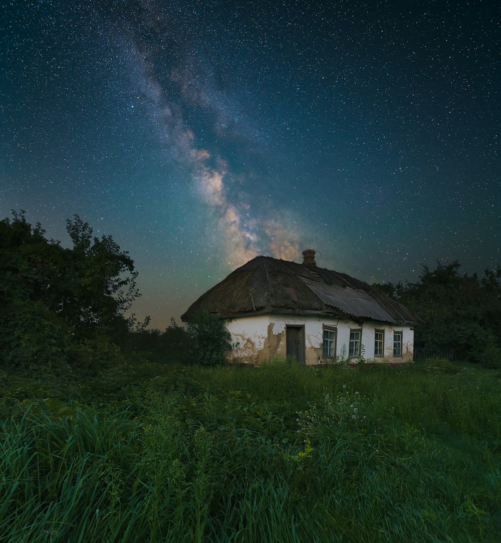 una casa in mezzo a un campo sotto un cielo notturno