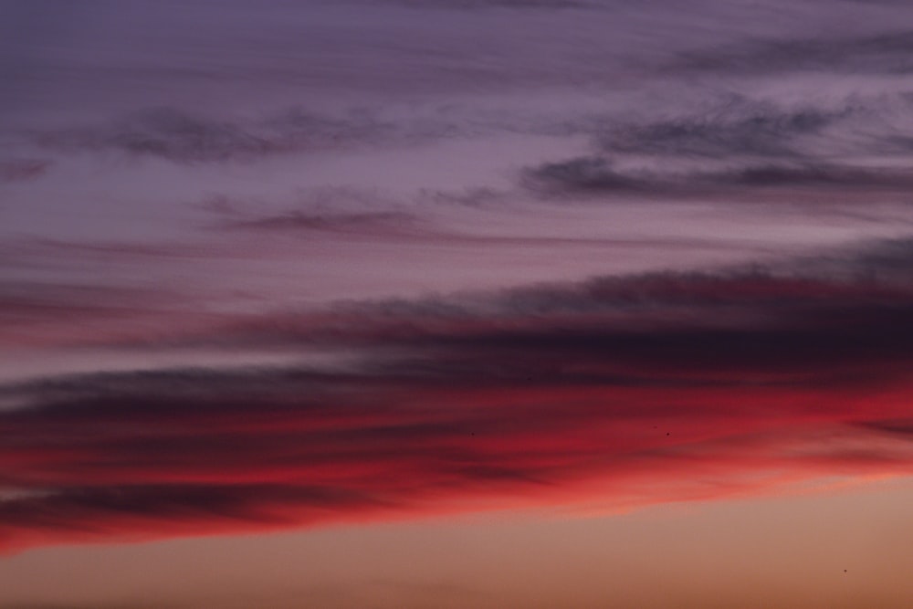 a plane flying in the sky at sunset