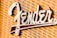 A close-up view of a metallic logo attached to a textured fabric background. The logo features a stylized font in a shiny metallic finish.