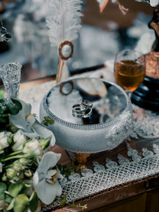 A selection of elegant wedding rings arranged on a wooden table with delicate flowers.