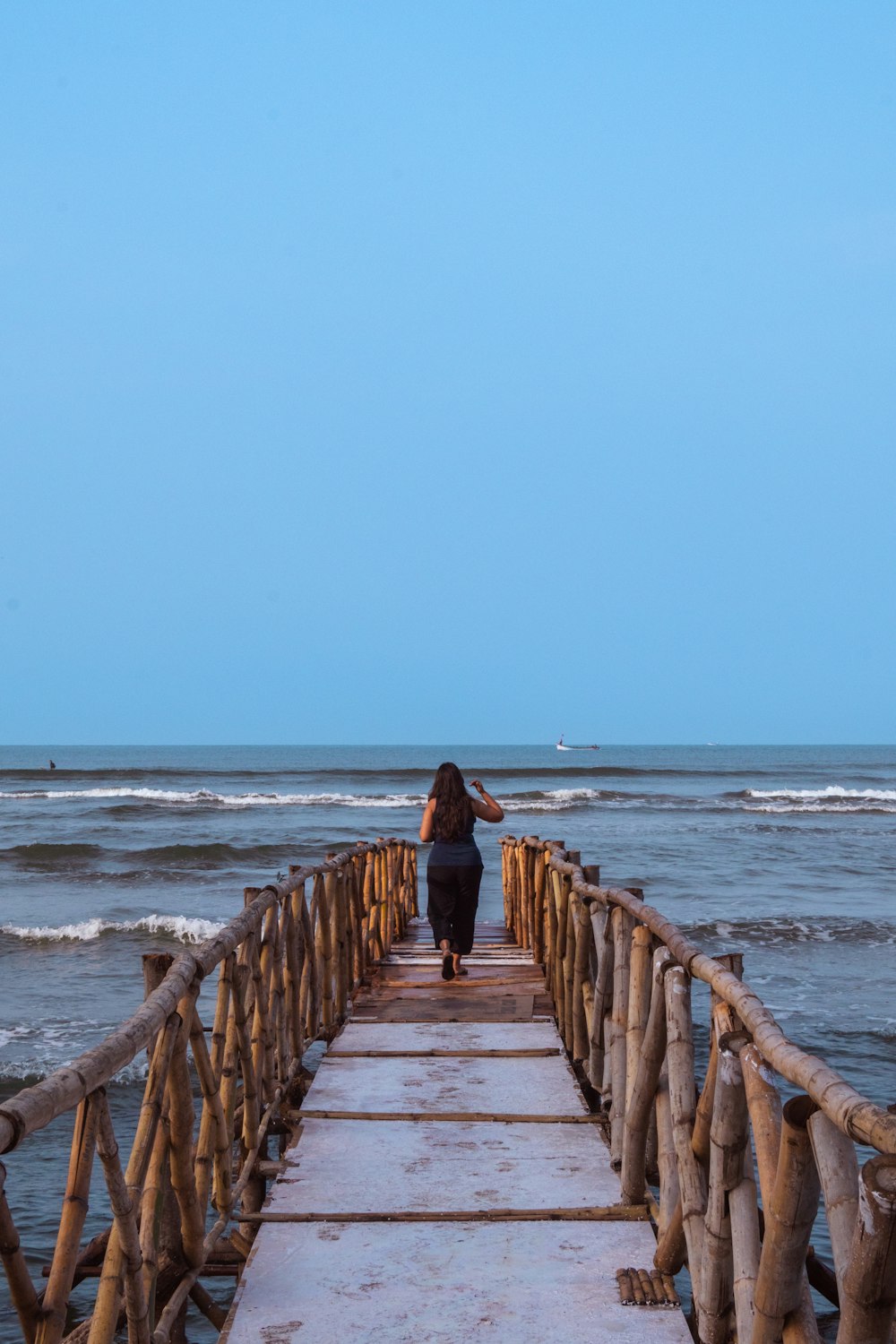 a woman walking across a wooden bridge over a body of water