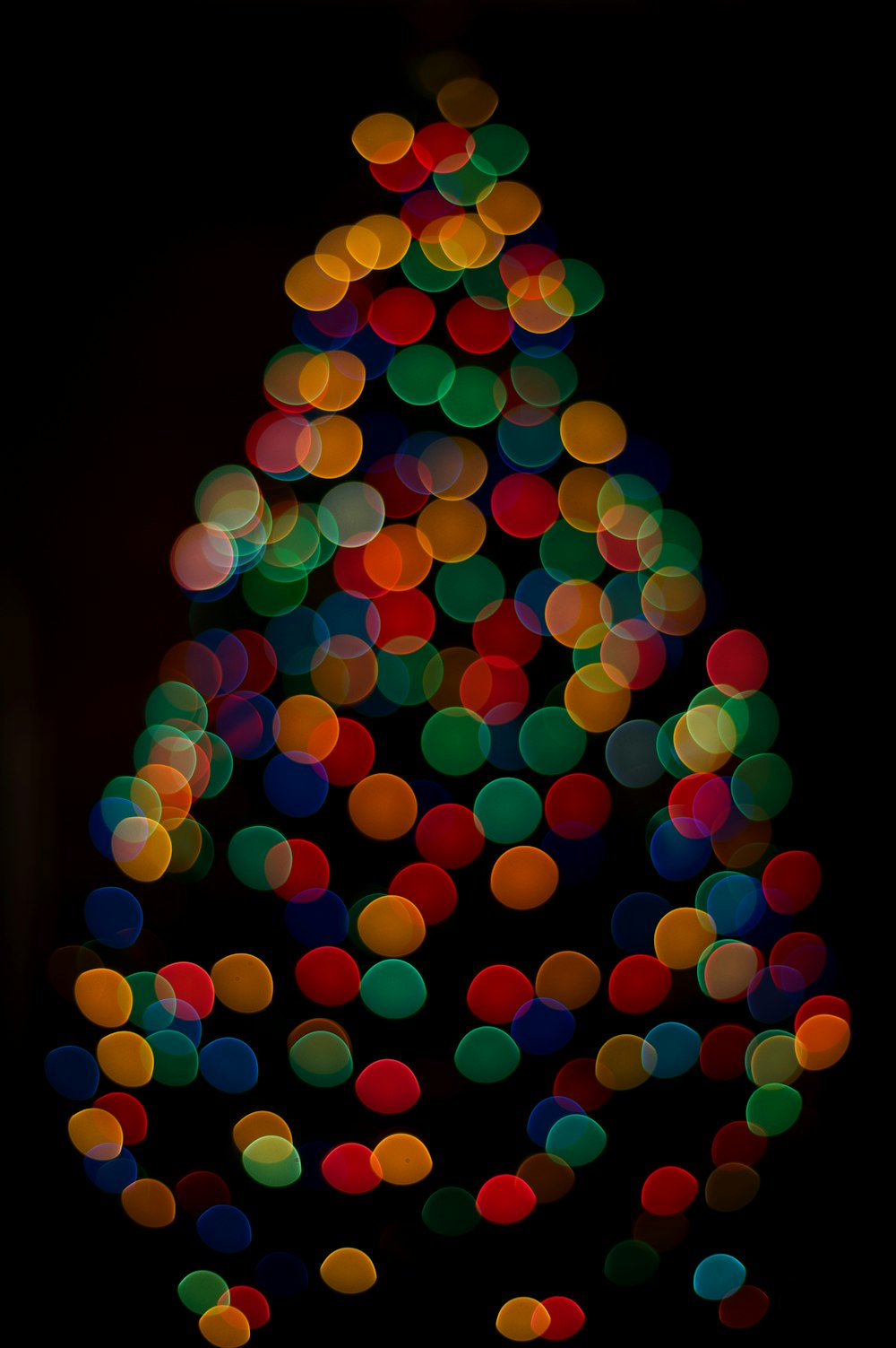 a multicolored christmas tree is lit up in the dark