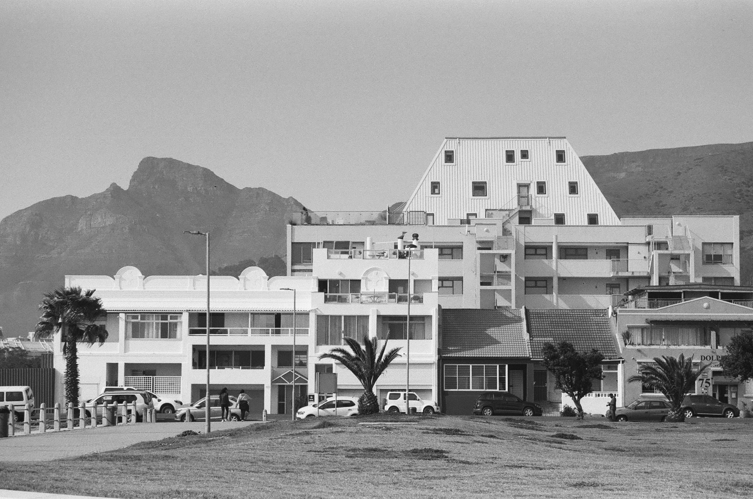 a black and white photo of a building with mountains in the background