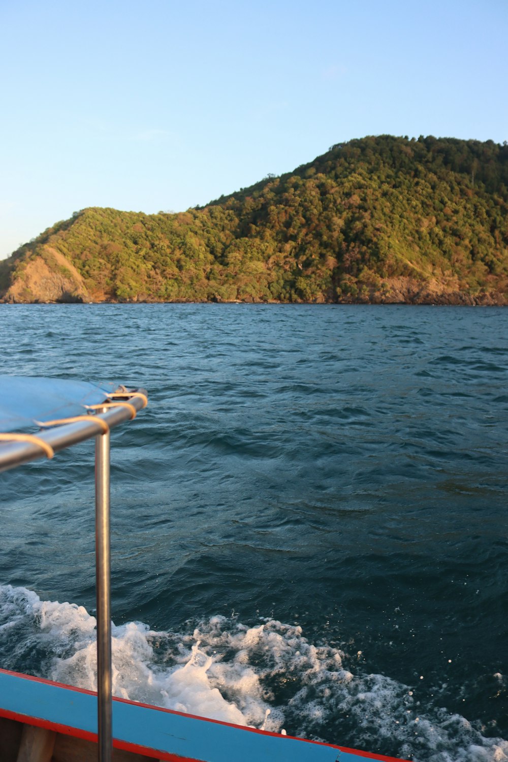 a boat traveling on a body of water with a mountain in the background