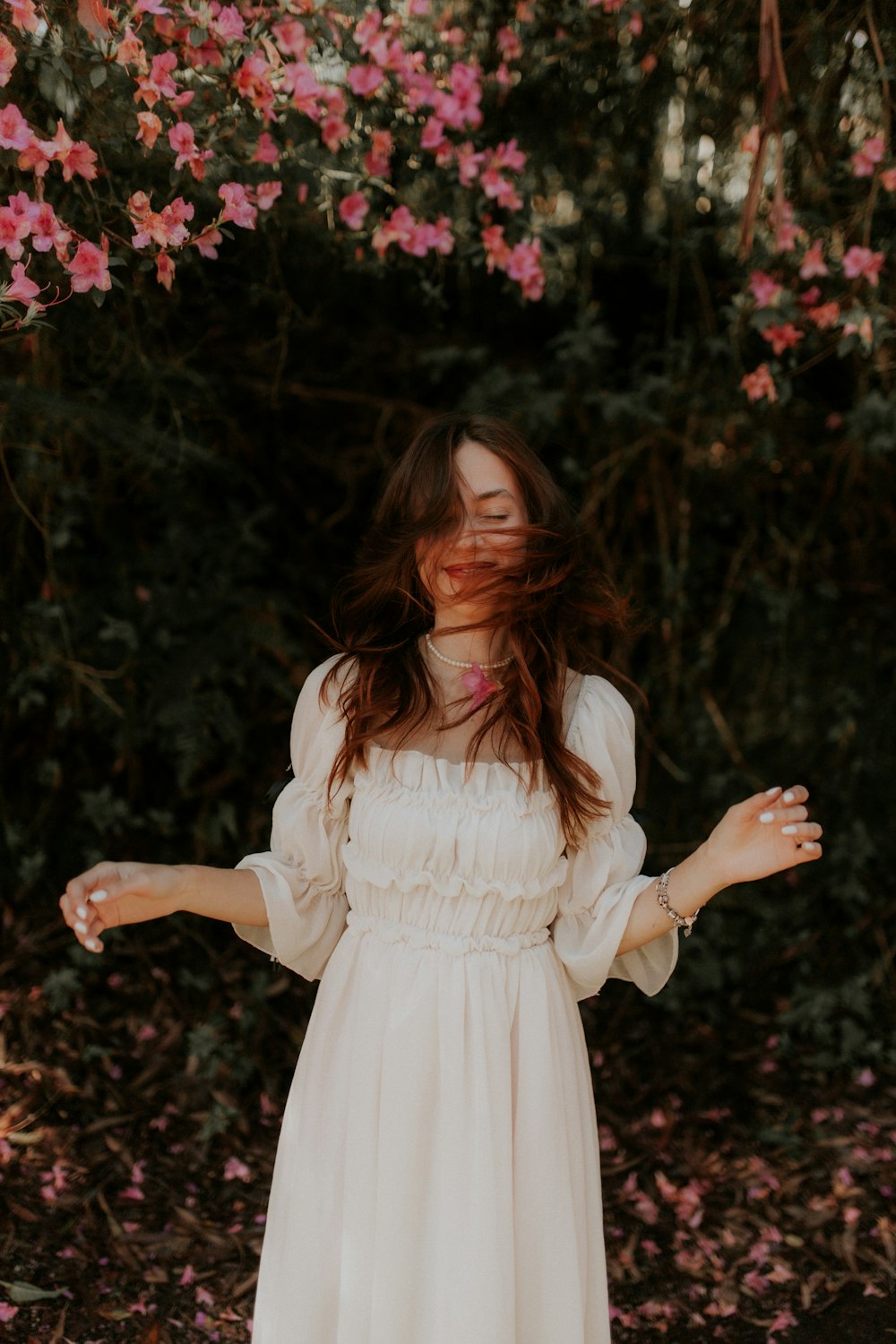 a woman in a white dress standing in front of pink flowers