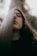 A person with closed eyes leans against a textured vertical surface, creating a tranquil and introspective atmosphere. The textured surface partially obscures the face, and soft, natural lighting enhances the serene mood.