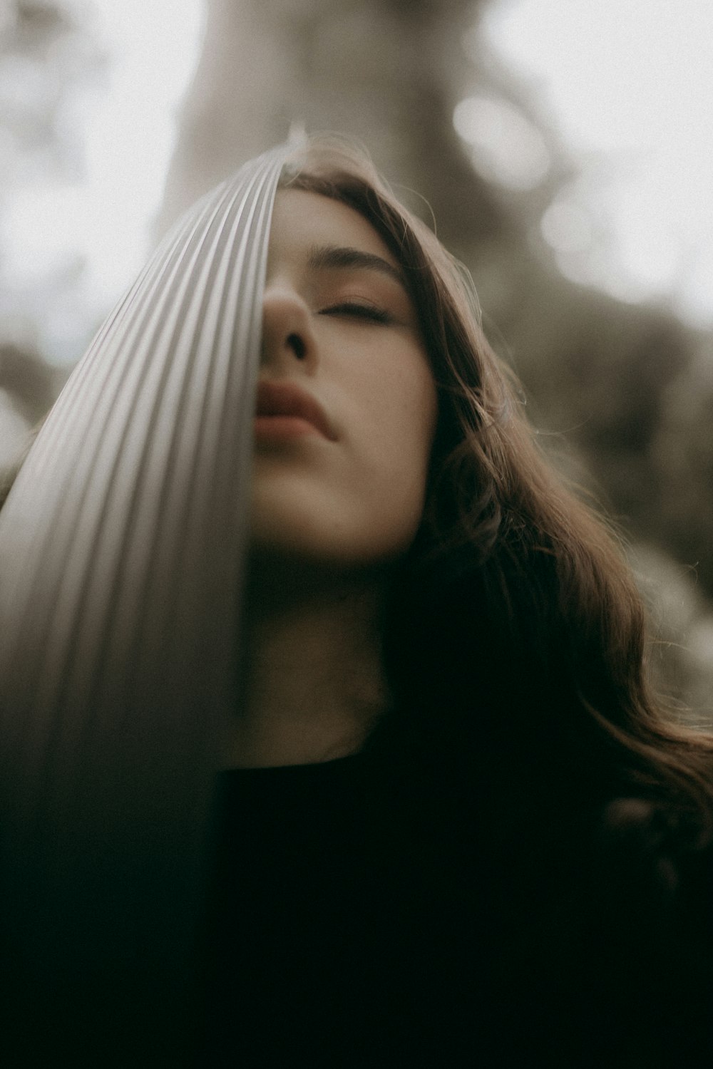 a woman with her eyes closed standing in a forest