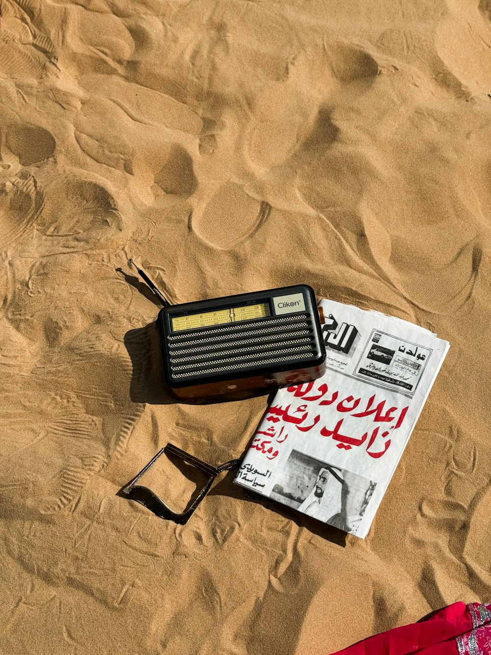 una radio e un paio di occhiali da sole sdraiati sulla sabbia