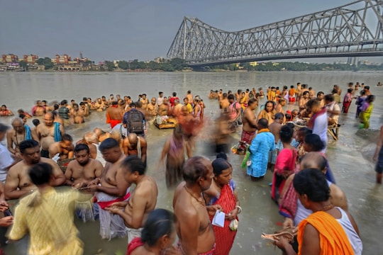 A crowd of pilgrims taking a holy dip in the flowing Godavari river under a bright sky.