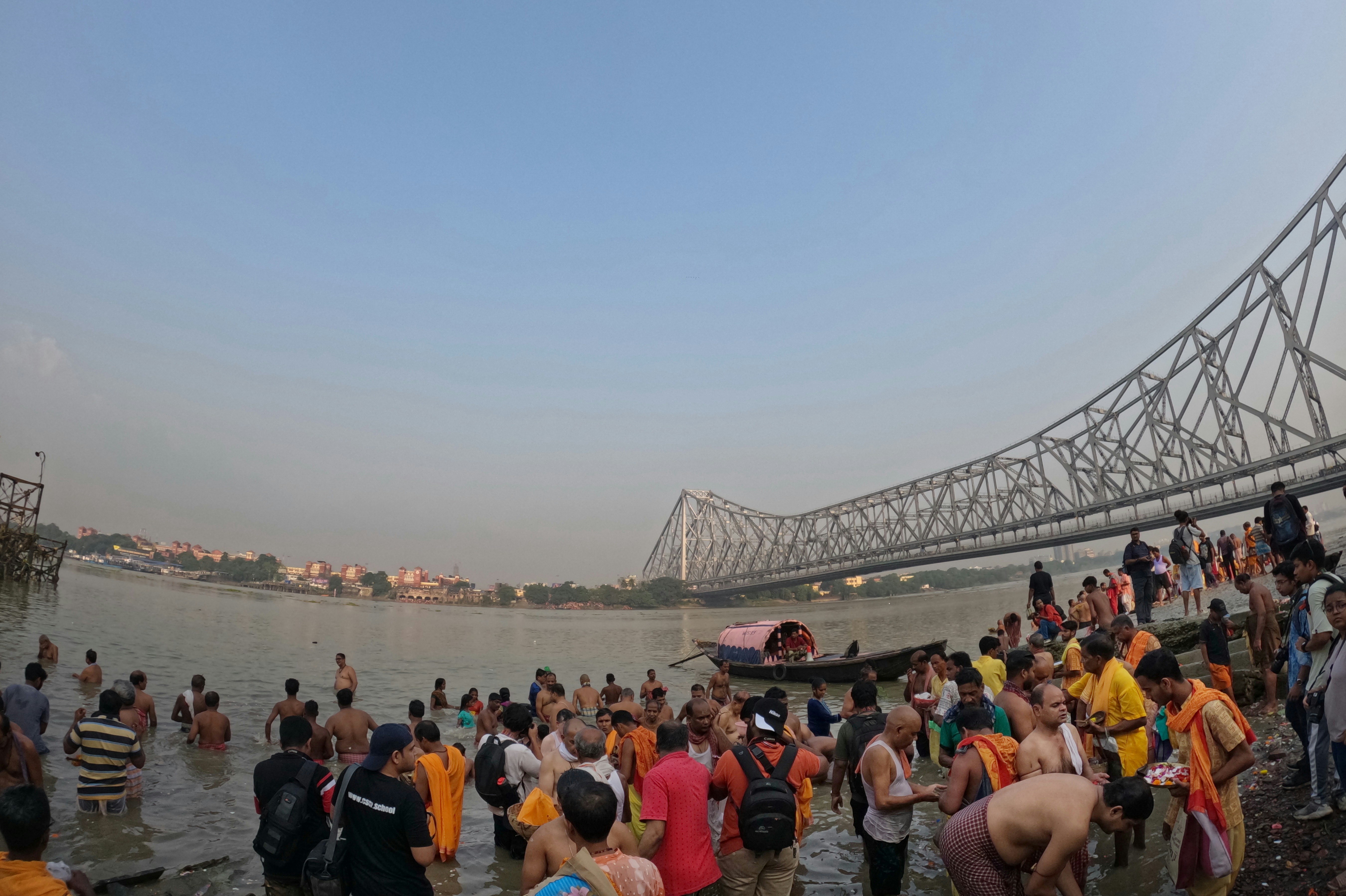 a group of people standing in the water near a bridge