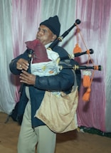 A friendly instructor demonstrating bagpipe techniques to a student in a cozy music room.