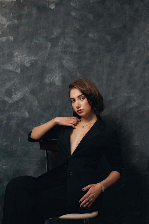 a woman in a black suit sitting on a chair