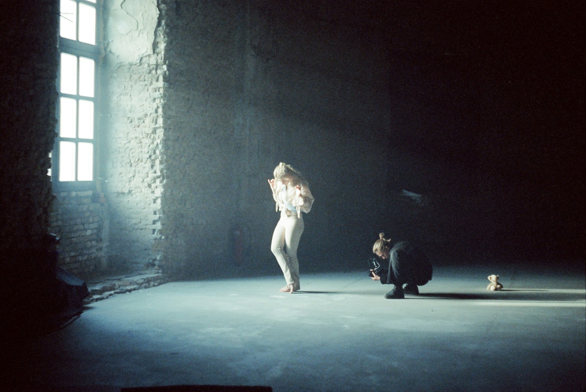 a woman standing in a dark room next to a window