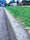 Close-up of a freshly stamped concrete driveway with a subtle pattern, bordered by green lawn and a suburban home.