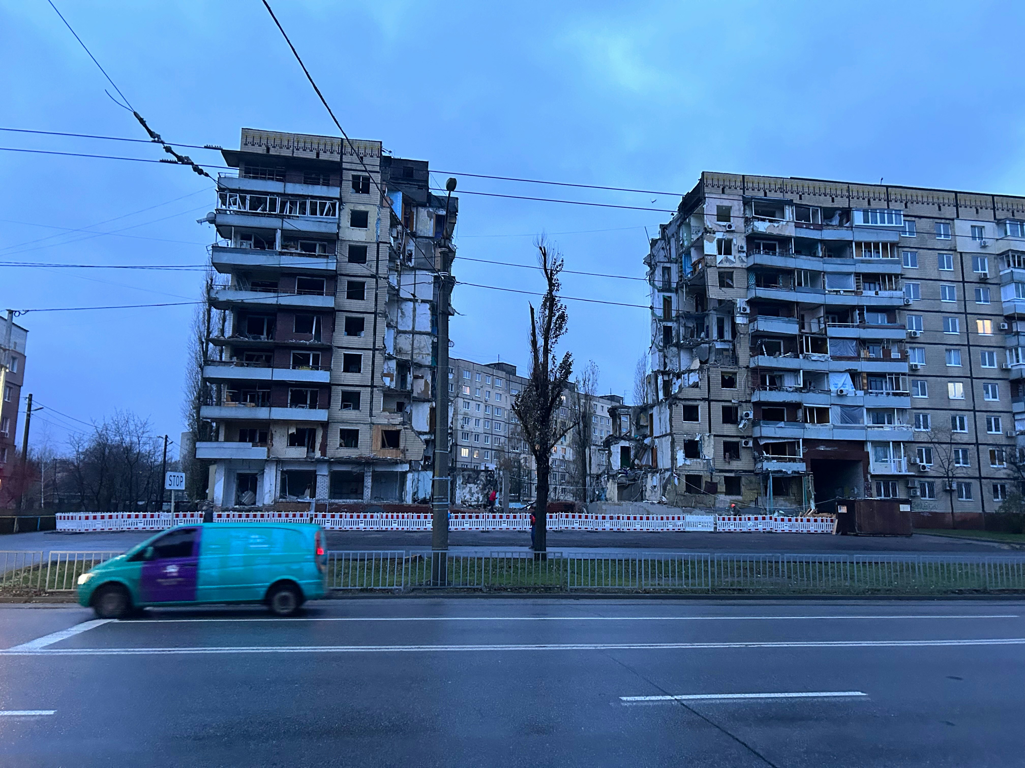 Une camionnette bleue roulant dans une rue à côté de grands immeubles