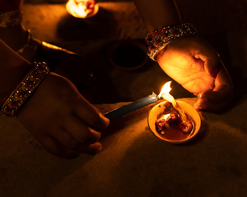 a person lighting a candle on a plate of food