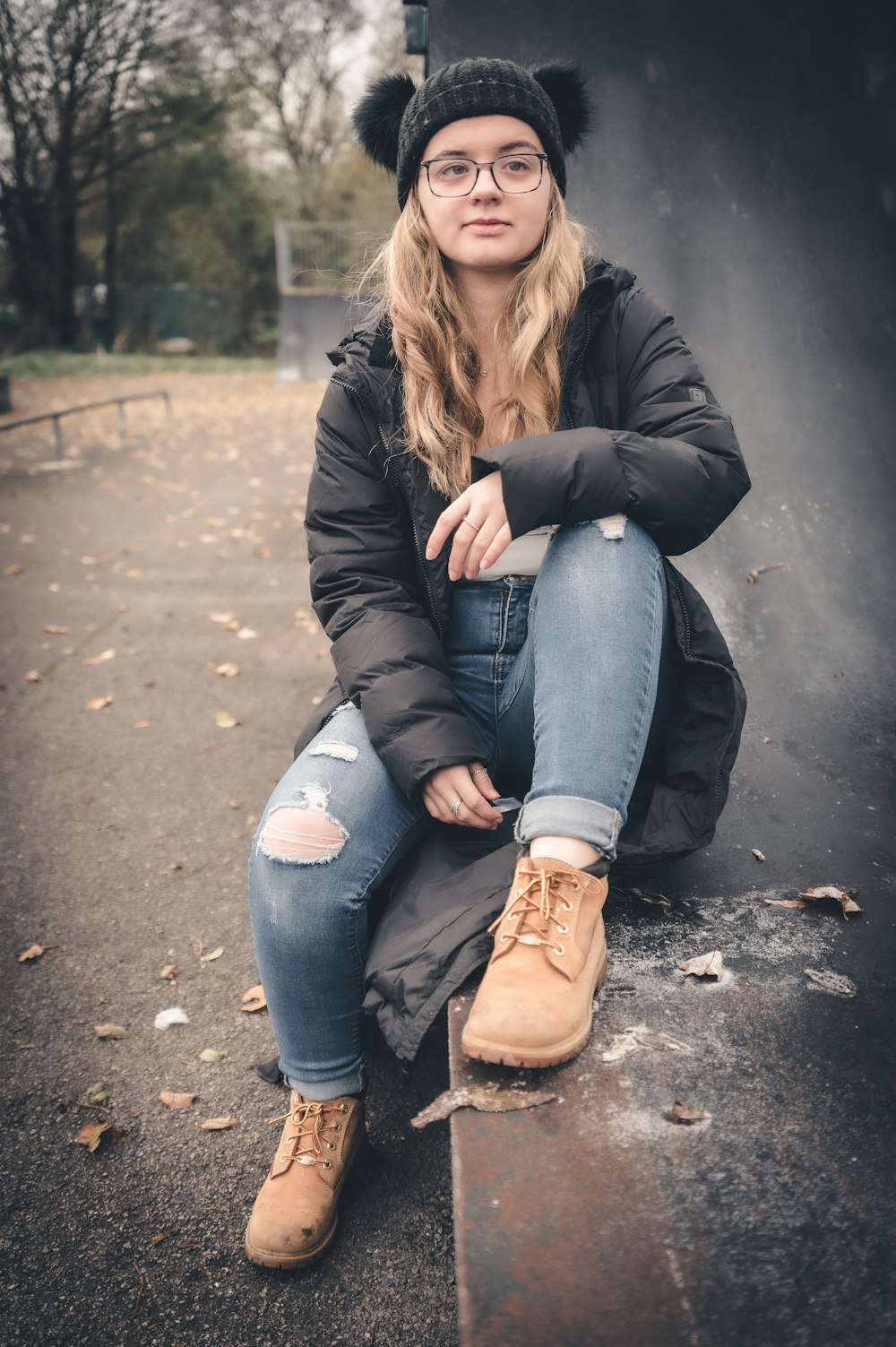 une femme assise sur un banc, coiffée d’un chapeau et de lunettes