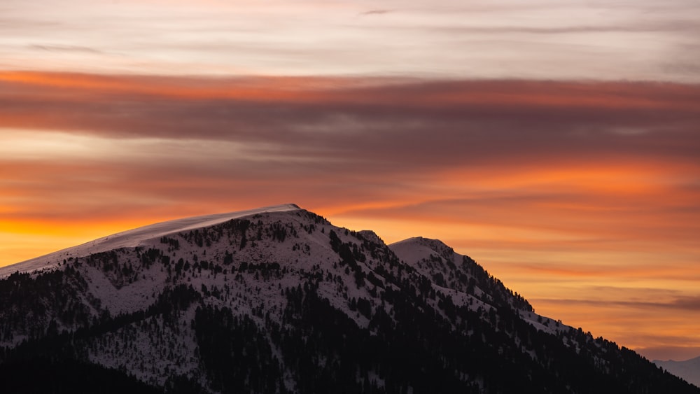 a snow covered mountain under a cloudy sky