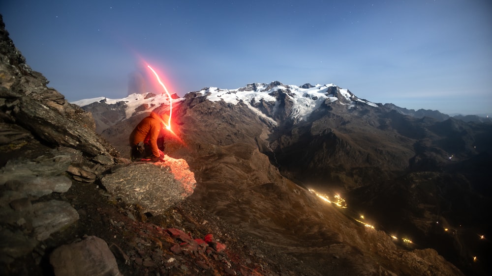 a man on top of a mountain holding a light saber
