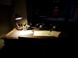 An elegant wooden desk with a vintage lamp casting light on strategic documents and blueprints.