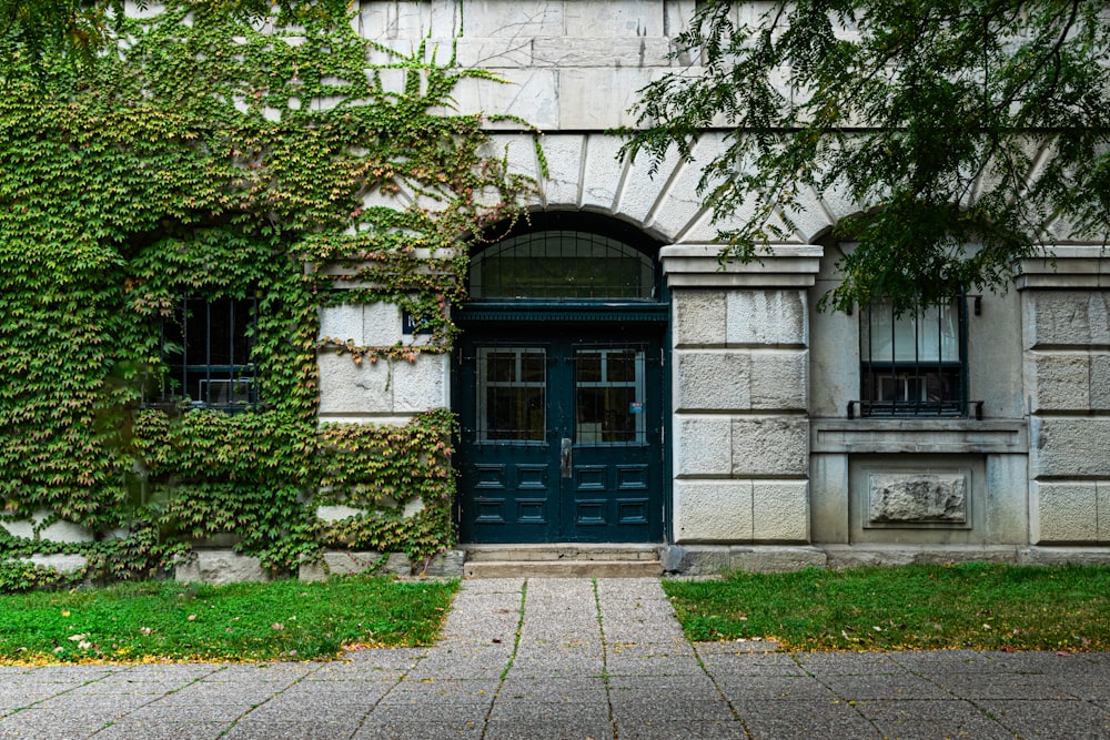 a building with a green door and ivy growing up the side of it