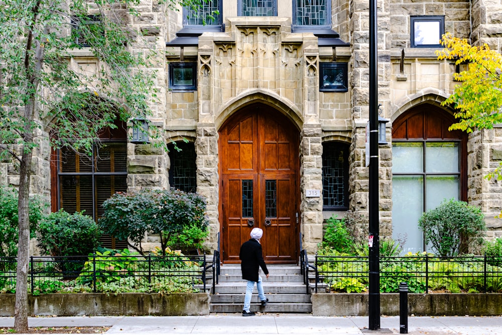 a man walking down a sidewalk past a tall building