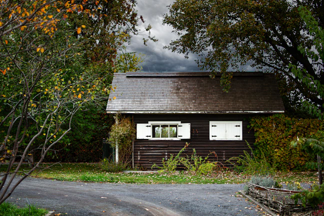 An old Appalachian cabin exterior framed by deep coal black shadows and teal-hued mist.