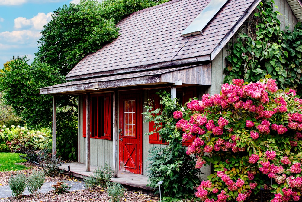 a small house with a red door surrounded by flowers