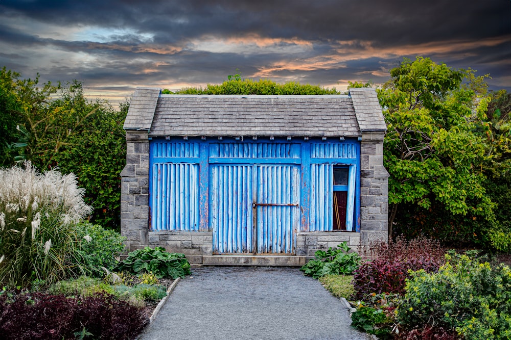 a blue building with a blue door in a garden