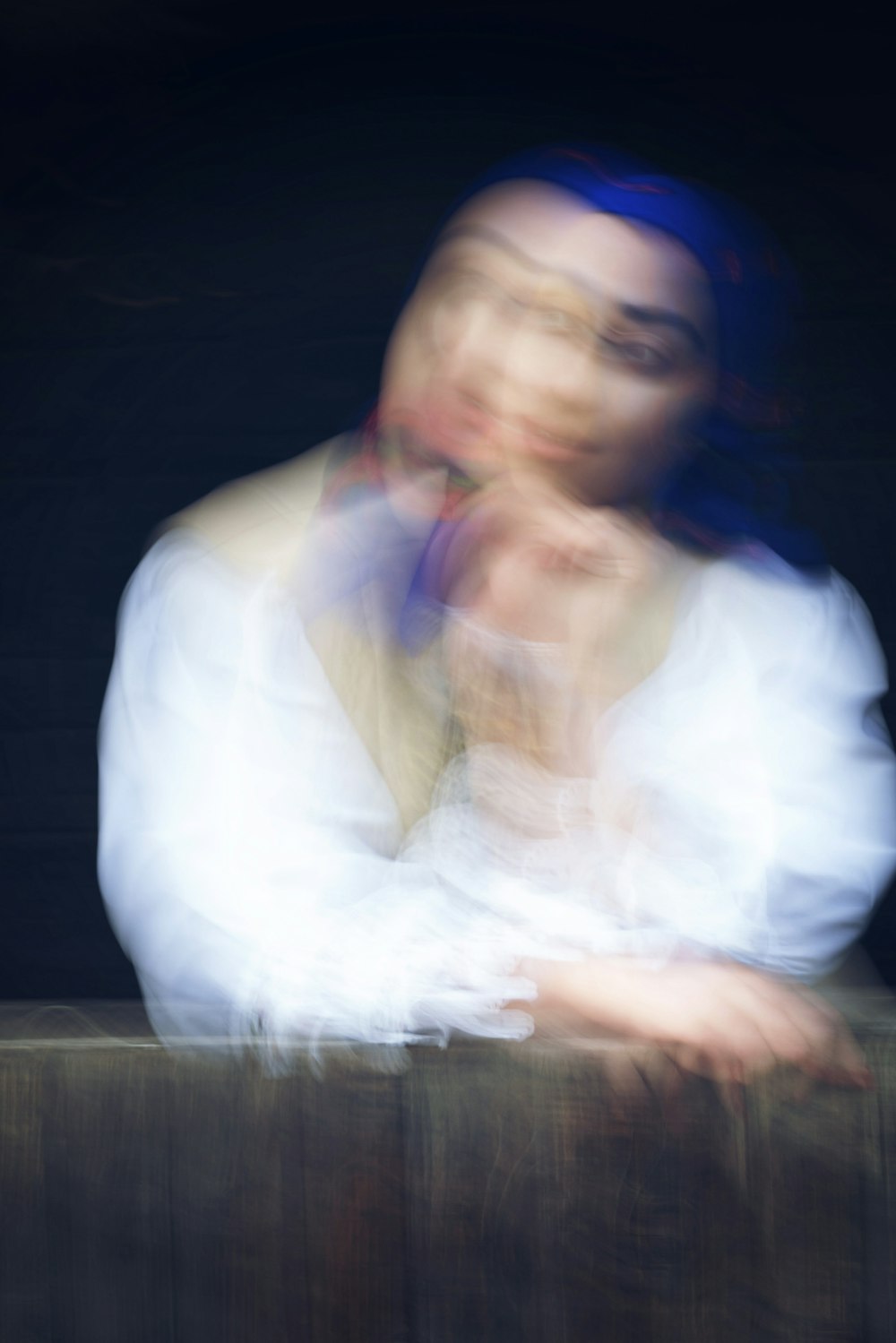 a blurry photo of a woman leaning on a wall