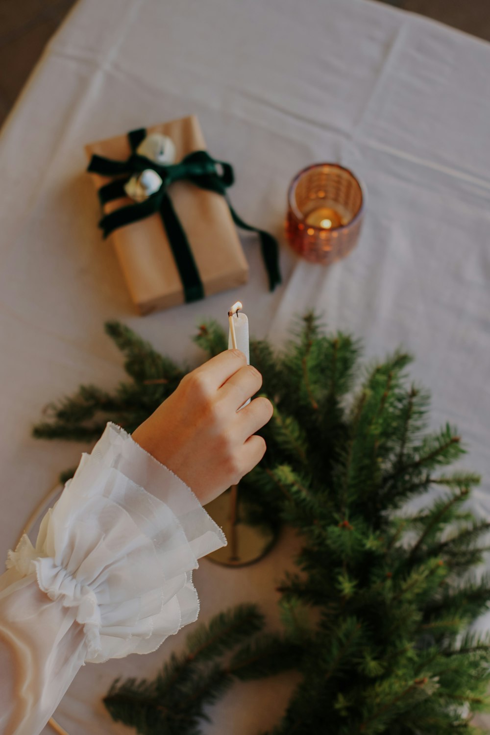 a person holding a candle next to a christmas tree