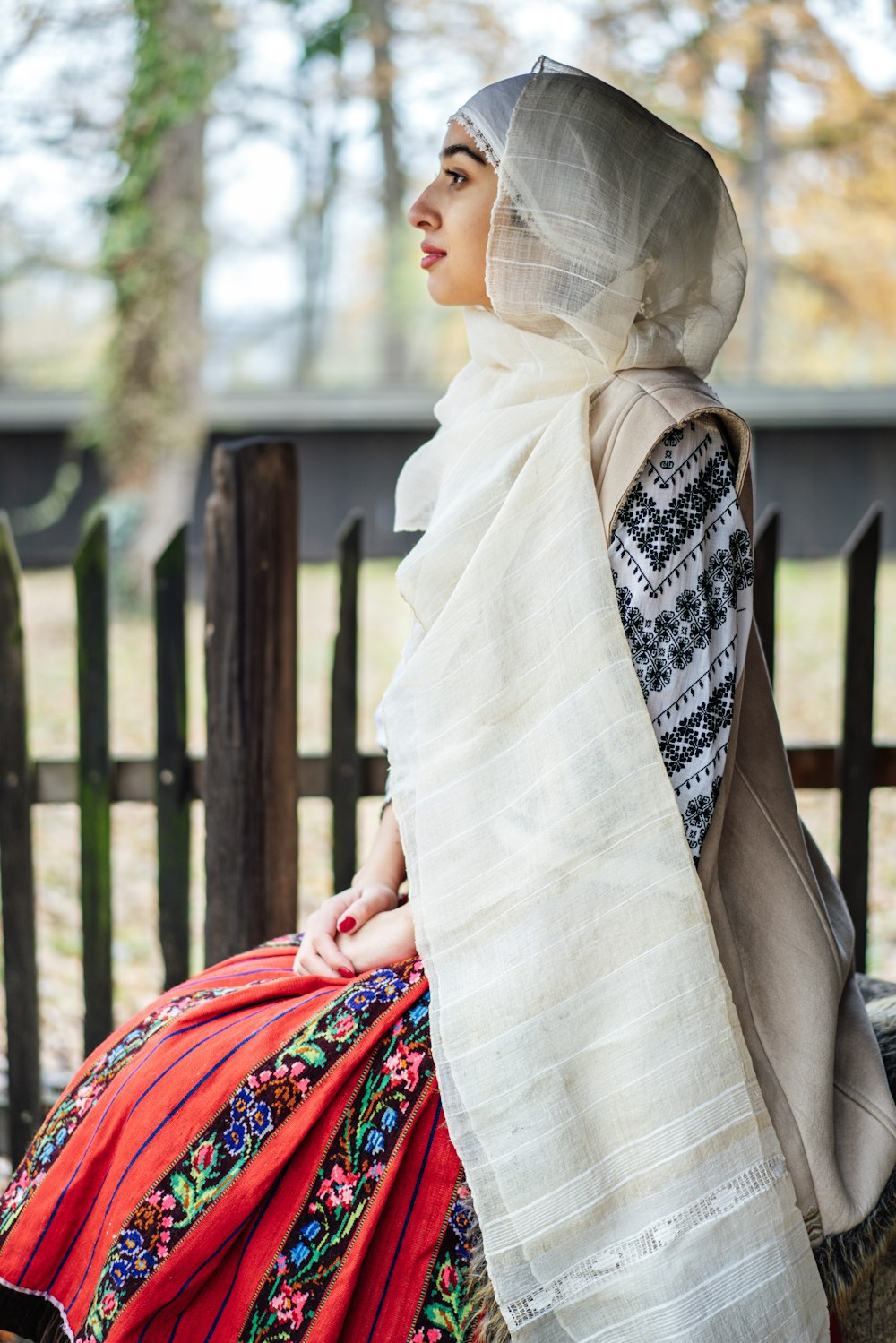 a woman sitting on a bench wearing a scarf