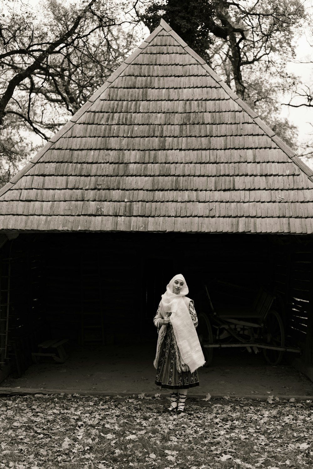 a woman in a dress and a hat is standing in front of a building