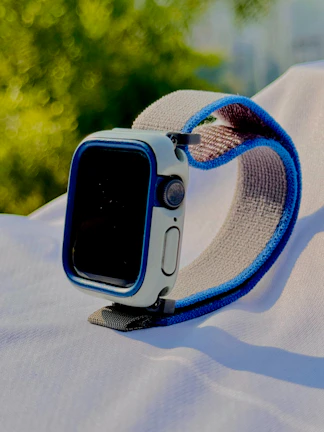 Close-up of a sleek smartwatch with a blue strap on a minimalist white background.