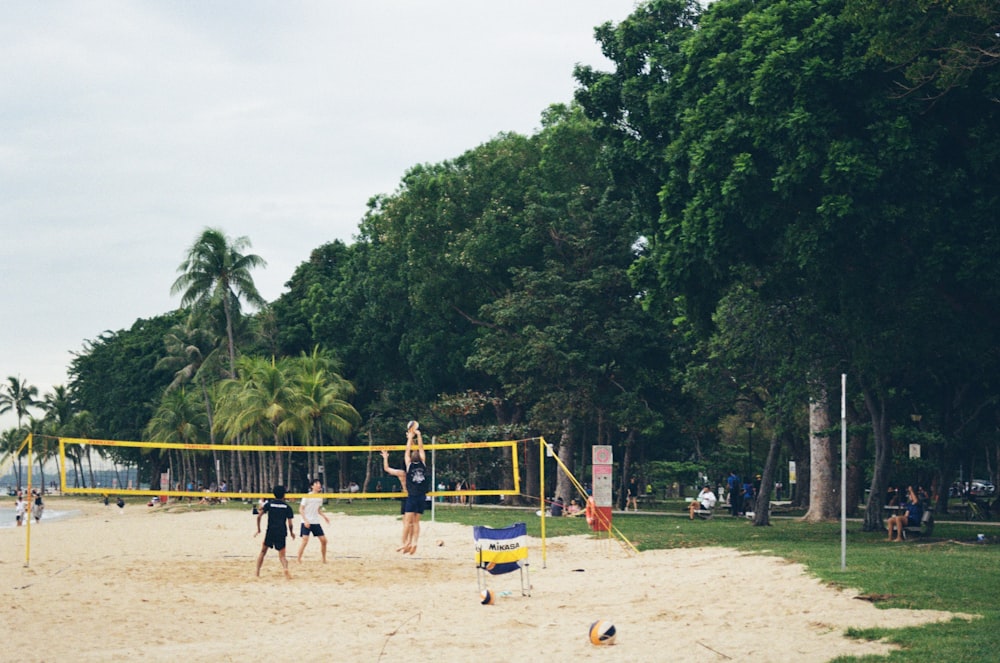 a group of people playing volleyball on a sandy beach