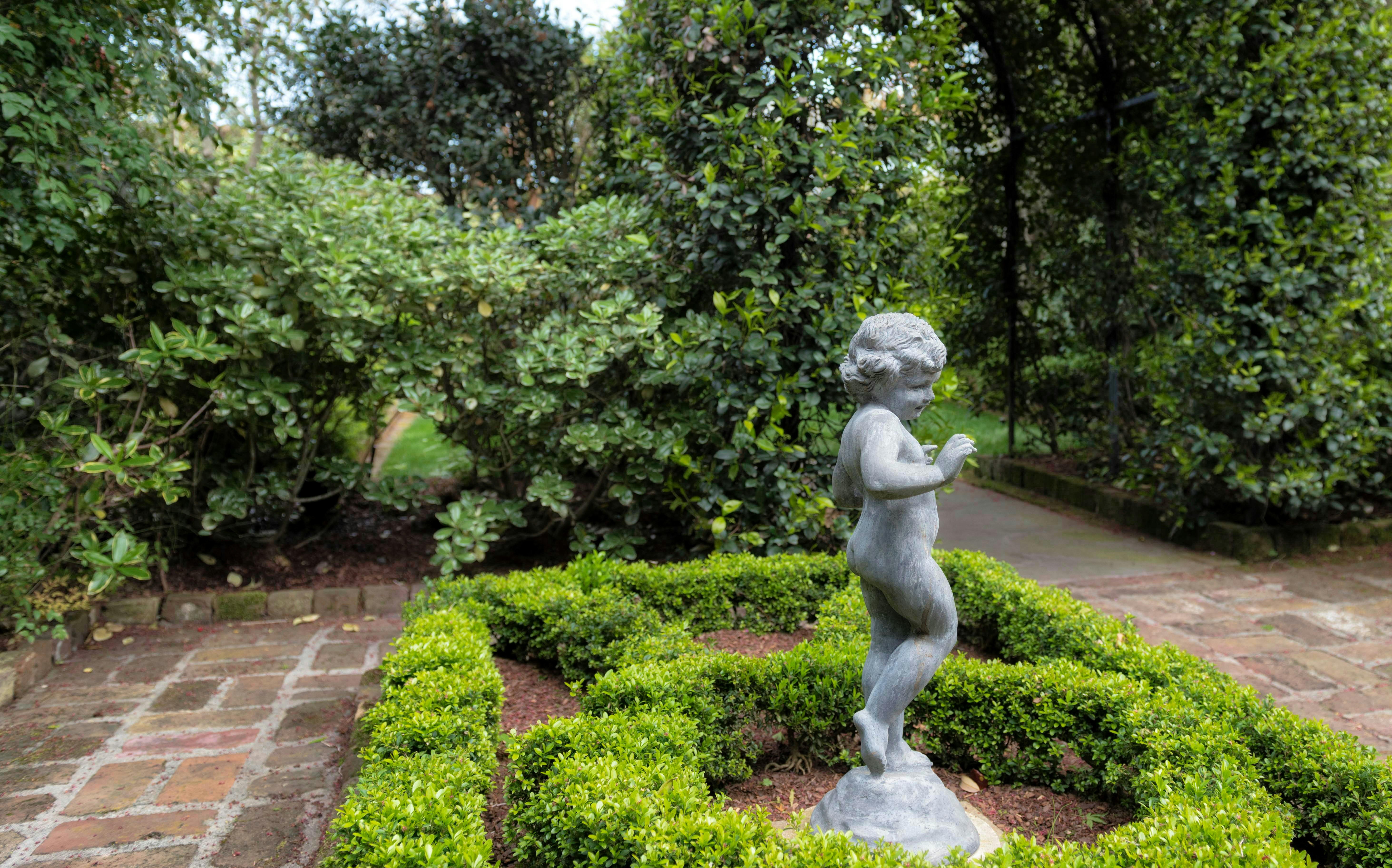 a small statue of a child in a garden