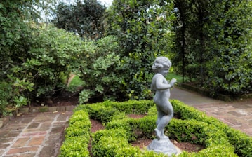 a small statue of a child in a garden